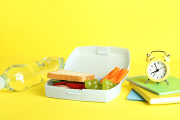 Sticker - Lunch box with snacks, bottle of water, alarm clock and books on yellow background