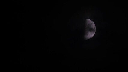 Wall Mural - Fast motion of first quarter moon or waxing gibbous moving among mysterious clouds at night. Telephoto view, real midnight footage with black background. Creepy halloween sky, astrology concept.
