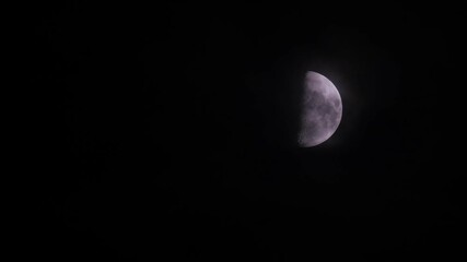 Wall Mural - First quarter moon or waxing gibbous with amazing craters moving among mysterious clouds at night. Telephoto view, real midnight footage with black background. Creepy halloween sky, astrology concept.