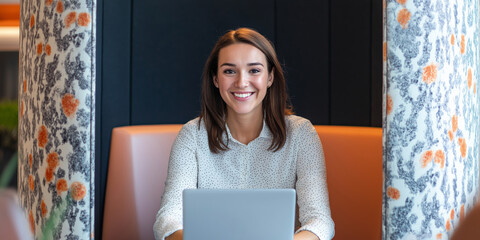 Wall Mural - A woman is sitting in front of a laptop with a smile on her face. She is wearing a white shirt and a black skirt