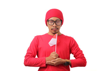 Indonesian youth holds a moment of silence while holding the Indonesian flag, remembering the struggle of the heroes who have fallen for Indonesia independence Day, isolated on a white background