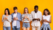 © Prostock-studio - Problematic smartphone use. Multiracial group of teenagers using mobile phones over yellow background, panorama