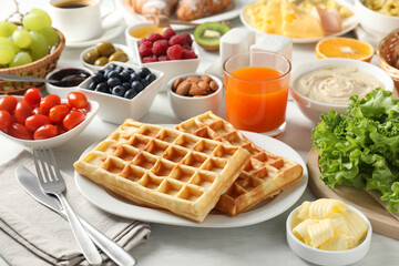 Sticker - Tasty breakfast. Belgian waffles, orange juice, butter and other food on light wooden table, closeup