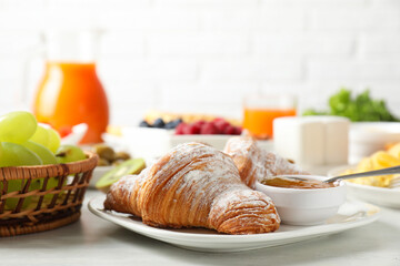 Wall Mural - Tasty breakfast. Croissants, jam and other food on light table, closeup