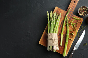 Poster - Fresh green asparagus stems, spices and knife on gray textured table, flat lay. Space for text