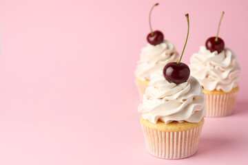 Wall Mural - Delicious cupcakes with cream and cherries on pink background, space for text