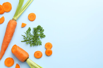 Wall Mural - Whole and cut fresh carrots with green leaf on light background, flat lay. Space for text