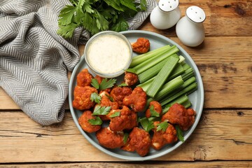 Wall Mural - Tasty cauliflower buffalo wings, sauce and celery on wooden table, flat lay