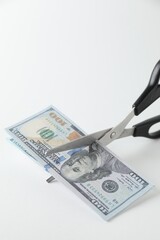 Wall Mural - Budgeting. Cutting dollar banknotes with scissors on white background, closeup