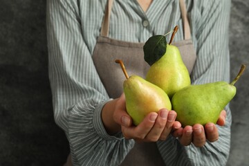 Wall Mural - Woman with ripe pears near grey wall, closeup