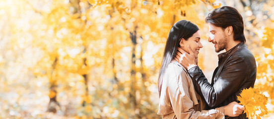 Wall Mural - Man in love touching his girlfriend face, dating in autumn forest, panorama with copy space