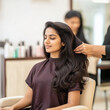 © Niks Ads - indian young woman getting her hair blow dried at a salon with maroon and cream color interior
