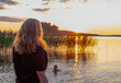 © Fox - Young woman relaxing on a lake and watching the sunset over the lake.