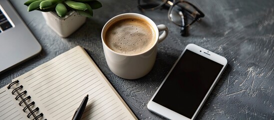 Wall Mural - Phone beside an empty notebook and coffee cup on a table. with copy space image. Place for adding text or design