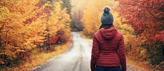 Poster - A female traveler is on a small local road admiring the vibrant autumn foliage on either side in Southern Vermont USA. with copy space image. Place for adding text or design