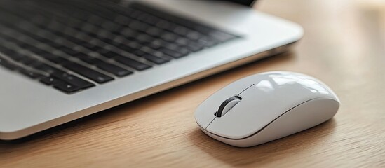 Poster - Close up of a modern white wireless mouse next to a black laptop on a wooden desk. with copy space image. Place for adding text or design