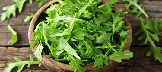 Wooden bowl filled with fresh green organic arugula, a healthy and delicious leafy green vegetable.