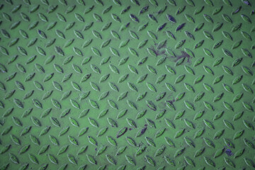 Close-up of green diamond plate metal texture with worn surface.