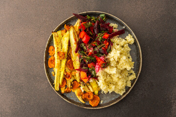 This nutritious meal features millet with baked zucchini and carrots, complemented by a vibrant salad of fresh seasonal vegetables and herbs