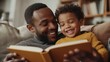 © Attasit - A father and son cuddling on a couch, sharing a book and laughter.