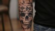 © Jojo - A forearm tattoo of a detailed skull with flowers growing out of the eye sockets, blending realism and surrealism