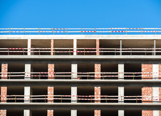 Construction of a multi-story building with safety barriers under a clear blue sky