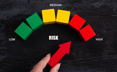 Risk management concept. Risk assessment level indicator rating, low to high on wooden block, black background. Business assess measurement. Hand red arrow point on green, yellow, red color. Top view