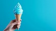 © Denys - Woman hand holding blue ice cream cone on turquoise background