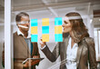 © peopleimages.com - Sticky notes, window and business people in office for brainstorming ideas, meeting and project planning. Corporate company, teamwork and man and woman writing for research, task agenda and schedule