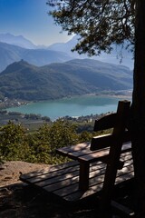 Vertical shot of rustic bench overlooking a stunning mountain lake and valley on a sunny day