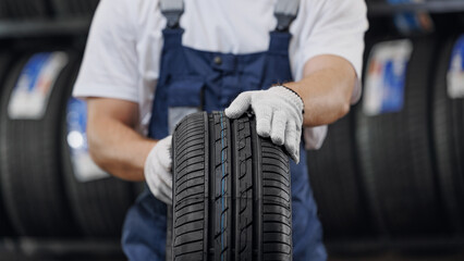 Wall Mural - Closeup mechanic holding new tire at store warehouse garage. Replacement of winter and summer tyres