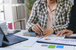 © amnaj - Business people reviewing financial reports and pointing at charts and graphs with documents, pen, laptop and mobile phone on a table