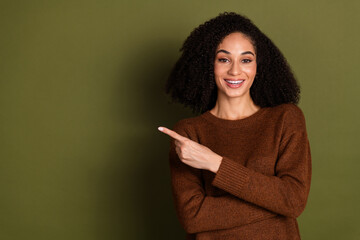 Poster - Portrait of pretty young woman indicate finger empty space wear sweater isolated on khaki color background