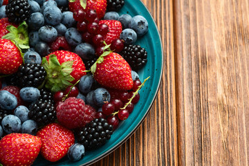 Wall Mural - Mix of ripe colorful berries in bowl photography . Blueberry , strawberry , raspberry , blackberry and red currant . Top view