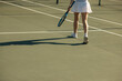 © Jacob Lund - Woman walking on tennis court with racket casting a shadow