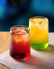 Canvas Print - Colorful cocktails on a wooden table on a dark blue background.