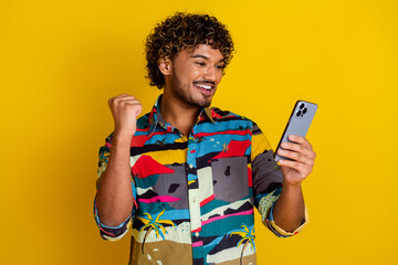 Wall Mural - Photo portrait of handsome young male hold device winning dressed stylish colorful garment isolated on yellow color background