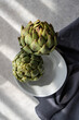 © RooM The Agency - Close-up overhead view of two artichokes in a bowl in sunlight