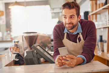 Fototapete - Happy businessman, barista and cafe with phone for online order, service or social media at coffee shop. Man, waiter or business owner with smile on mobile smartphone for review at indoor restaurant