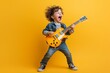 © Ace64 Studio - A young boy playing an electric guitar, his hair standing on end, shouting and having fun against a yellow background. The child is dressed in jeans and sneakers and has dark brown eyes.