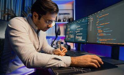 Working smart IT developer writing data software development from two pc screen, creating application program updated version online website page system online at neon light cyber office. Surmise.