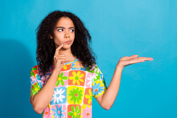 Poster - Photo of attractive doubtful lady dressed flower print t-shirt holding arm empty space isolated blue color background