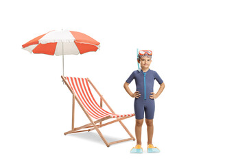 Wall Mural - Full length portrait of a boy in a wetsuit, diving mask and flippers posing next to a beach lounger