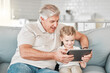 © DavisShared/peopleimages.com - Happy, sofa and grandfather with kid on tablet for watching videos, online cartoons and streaming movies. Family, home and grandpa with girl on digital tech for bonding, relationship and relax