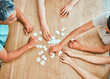 © peopleimages.com - Collaboration, hands and puzzle with group of business people at wooden table from above for teamwork. Building, effective or synergy and team with jigsaw pieces for development, growth or planning