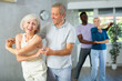 © JackF - Dynamic mature attendees of dancing courses training poses of Waltz in dance hall