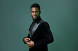 © SHOTPRIME STUDIO - Elegant african american man in black tuxedo posing confidently against vibrant green background