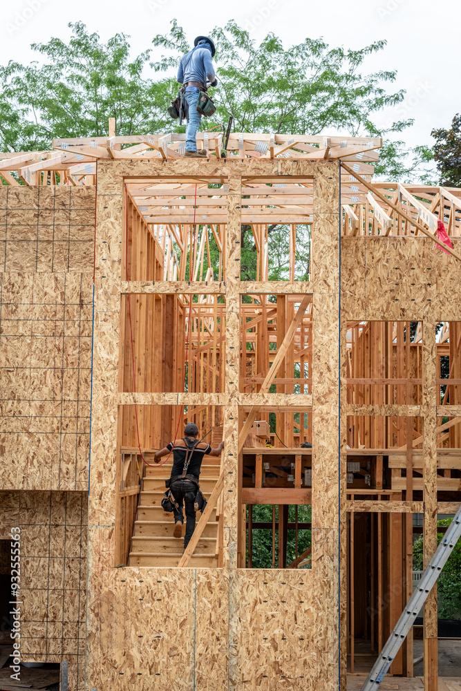 New residential home construction in framing stage, workman on the roof ...