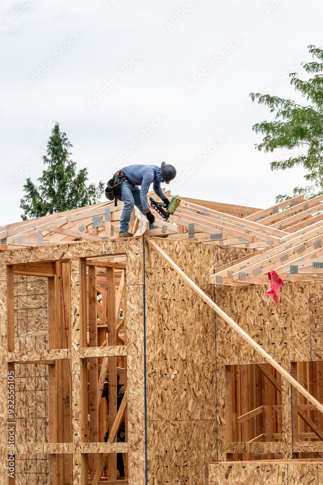New residential home construction in framing stage, workman on the roof ...