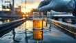 © busro - Water quality test being conducted by an environmental engineer in protective gloves at a reservoir, with a blurred view of the water treatment plant in the background
